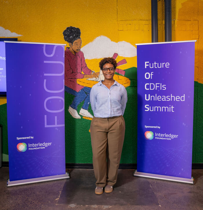 Casey DikƩ standing in front of the mural and FOCUS banners.